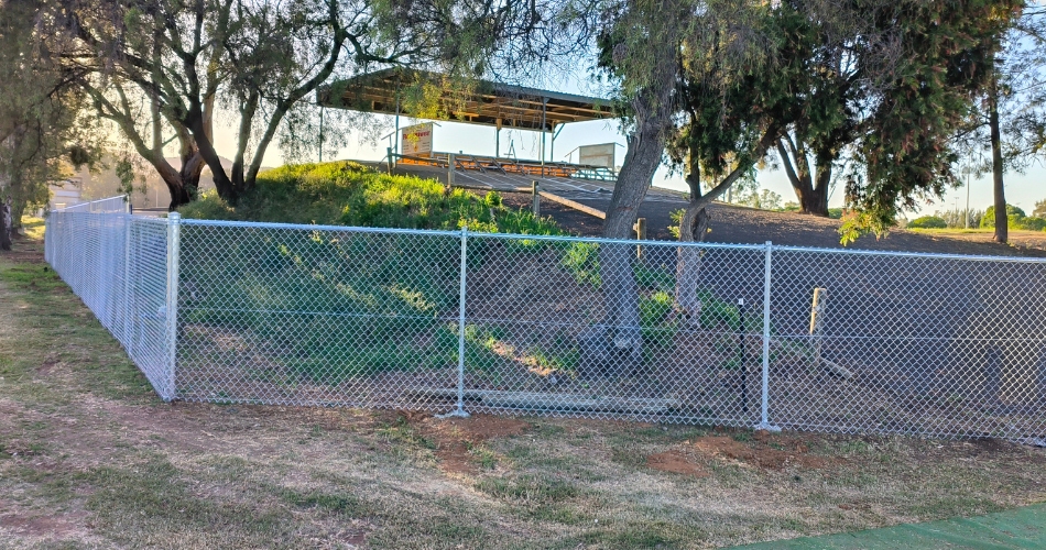 New mesh fence with sun pearing over hill inside it