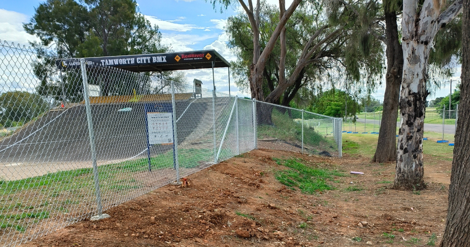 New mesh fence with bmx hill start in background behind it