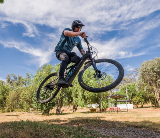 An image of a bike rider jumping a dirt ramp.